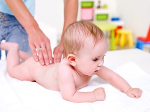 Mother massaging body of newborn baby - indoors